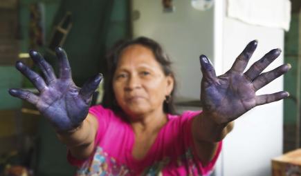 A woman shows her stained hands.