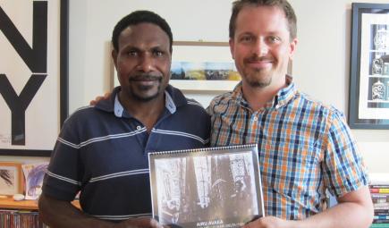 Curators holding spiral-bound translated monograph