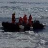 Researchers standing in a launch between ice floes in Antarctica