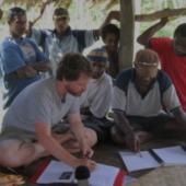 Linguist and knowledge bearer work with notebooks in open hut