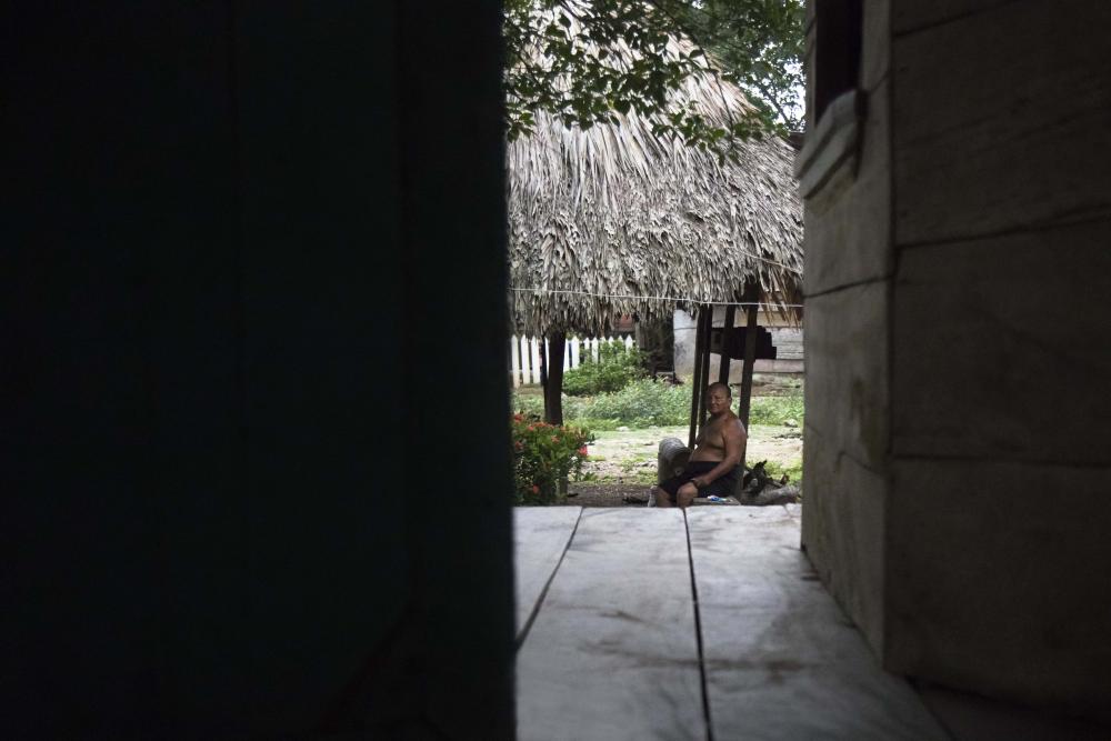 A man sits outside his home.